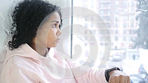 Afro-american woman waiting and watching time, sitting at window