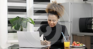 Afro american woman wearing headphones studying online from home