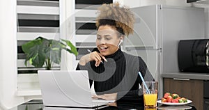 Afro american woman wearing headphones studying online from home