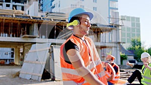 Afro American worker at construction site dancing charismatic while have a break listening music from the headphones he