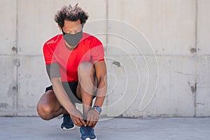 Afro athletic man tying his shoelaces.