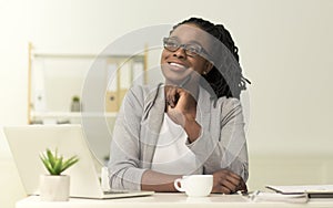 Afro Businesswoman Sitting At Laptop Imagining Something In Office