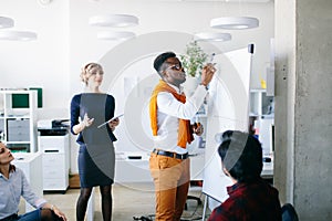 Afro cheif is writing a graph on the flipchart to his colleagues