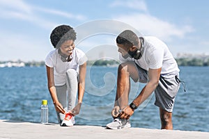Afro Couple Lacing Shoes Preparing For Morning Jog Outside