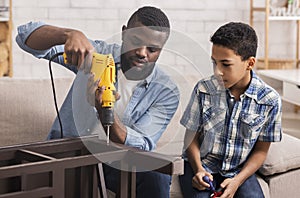 Afro Dad Teaching Preschool Son To Use Electric Drill At Home