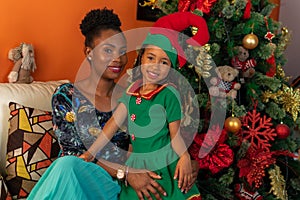 Afro-descendant Colombian Latins mother and daughter sitting on the sofa next to the Christmas tree photo