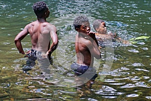 Children playing in a pool at the base of a waterfall in Ecuador