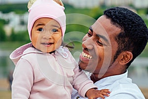 Afro father hugging her mixed race daughter spending time in garden