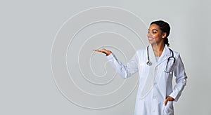 Afro Female Doctor Holding And Looking At Some Invisible Object On Her Palm