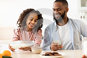 Afro Girl And Dad Having Breakfast Pouring Milk In Cereal