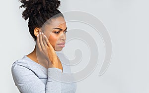 Afro girl suffering from otitis, rubbing her inflamated ear