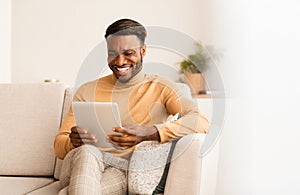 Afro Guy Using Tablet Computer Sitting On Couch At Home
