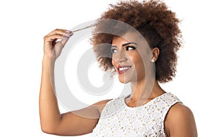 Afro hair black brazilian girl smiling cheerfully and holding hair. Concept of hair care. Standing against white background