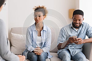 Afro Husband Playing Phone Visiting Couples Therapy With Wife