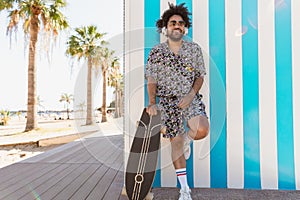 Afro Latin man having fun listening music with headphones on tropical beach during vacation