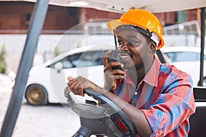 Afro loader worker is talking on the walkie-talkie in forklift