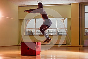 Afro man doing exercise with a fit box in a gym