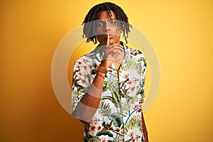Afro man with dreadlocks on vacation wearing summer shirt over isolated yellow background asking to be quiet with finger on lips