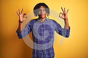 Afro man with dreadlocks wearing casual shirt standing over isolated yellow background relax and smiling with eyes closed doing