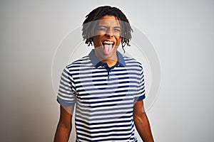 Afro man with dreadlocks wearing striped blue polo standing over isolated white background sticking tongue out happy with funny