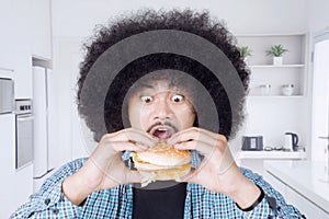 Afro man eating big cheeseburger