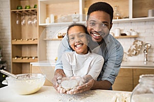 Afro man holding daughter hands with heart shaped pastry inside