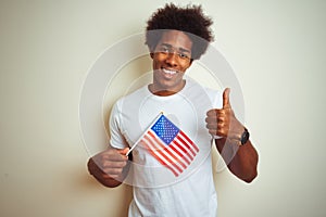 Afro man holding United Estates of America USA flag standing over isolated white background happy with big smile doing ok sign,