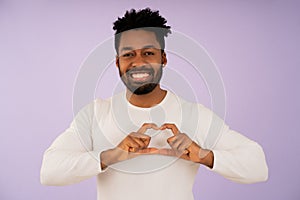 Afro man smiling while making a heart with her hands.