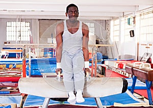 afro man in sportswear doing exercises on pommel horse