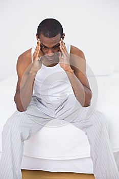Afro man suffering from headache in bed