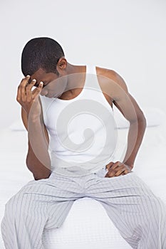 Afro man suffering from headache in bed