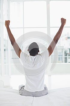 Afro man waking up in bed and stretching his arms