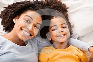 Afro Mother And Daughter Lying In Bed In Bedroom, Top-View