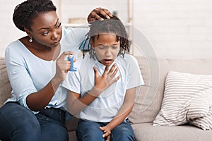 Afro mother holding asthma inhaler for daughter photo