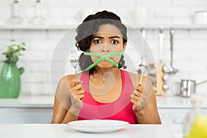 Afro woman with green measuring tape around her mouth