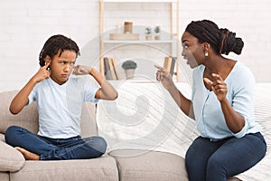 Afro woman lecturing her child who closing ears