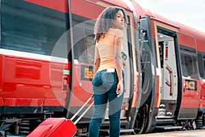 Afro woman ready to take the train with carry on baggage trolley