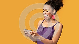Afro woman using mobile phone playing games at studio