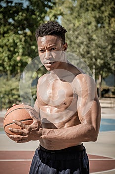 Afroamerican young man playing street basketball in the park