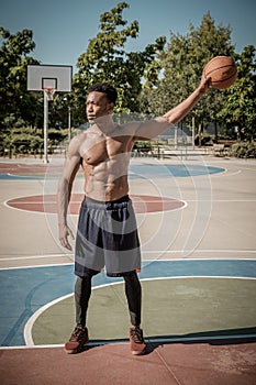 Afroamerican young man playing street basketball in the park