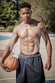 Afroamerican young man playing street basketball in the park