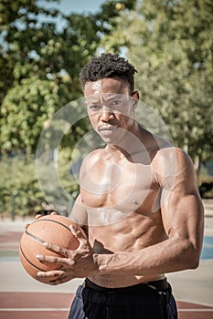 Afroamerican young man playing street basketball in the park