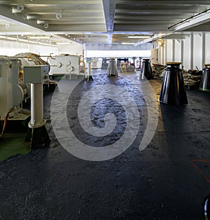 Aft mooring station situated on stern part of container ship behind superstructure. On the green painted main deck are white ropes