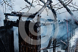 Aftermath of fire disaster. Smoke after great fire. Burned down to the ground wooden house.