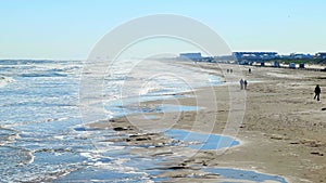 Afternoon beach scene at the Gulf of Mexico with sand, waves, cars and people enjoying themselves on a sunny day