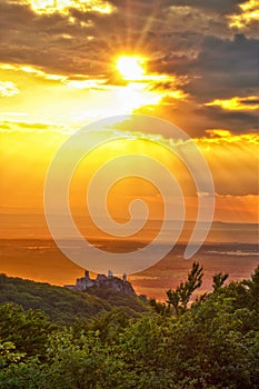 Zrúcanina Plaveckého hradu stojaca na zelenom kopci pri západe slnka