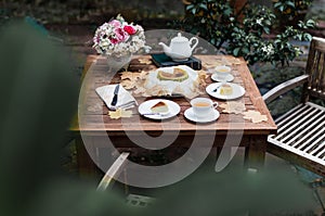 Afternoon tea basque burnt cheesecake and tea cup with teapot on wooden table.