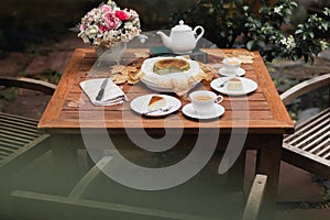 Afternoon tea basque burnt cheesecake and tea cup with teapot on wooden table.