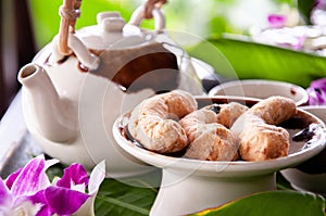 Afternoon tea in ceramic pot and butter cookies among flower