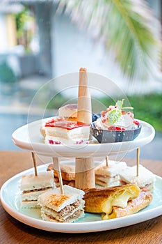 Afternoon tea with fresh cakes, pastries and sandwiches with hot tea